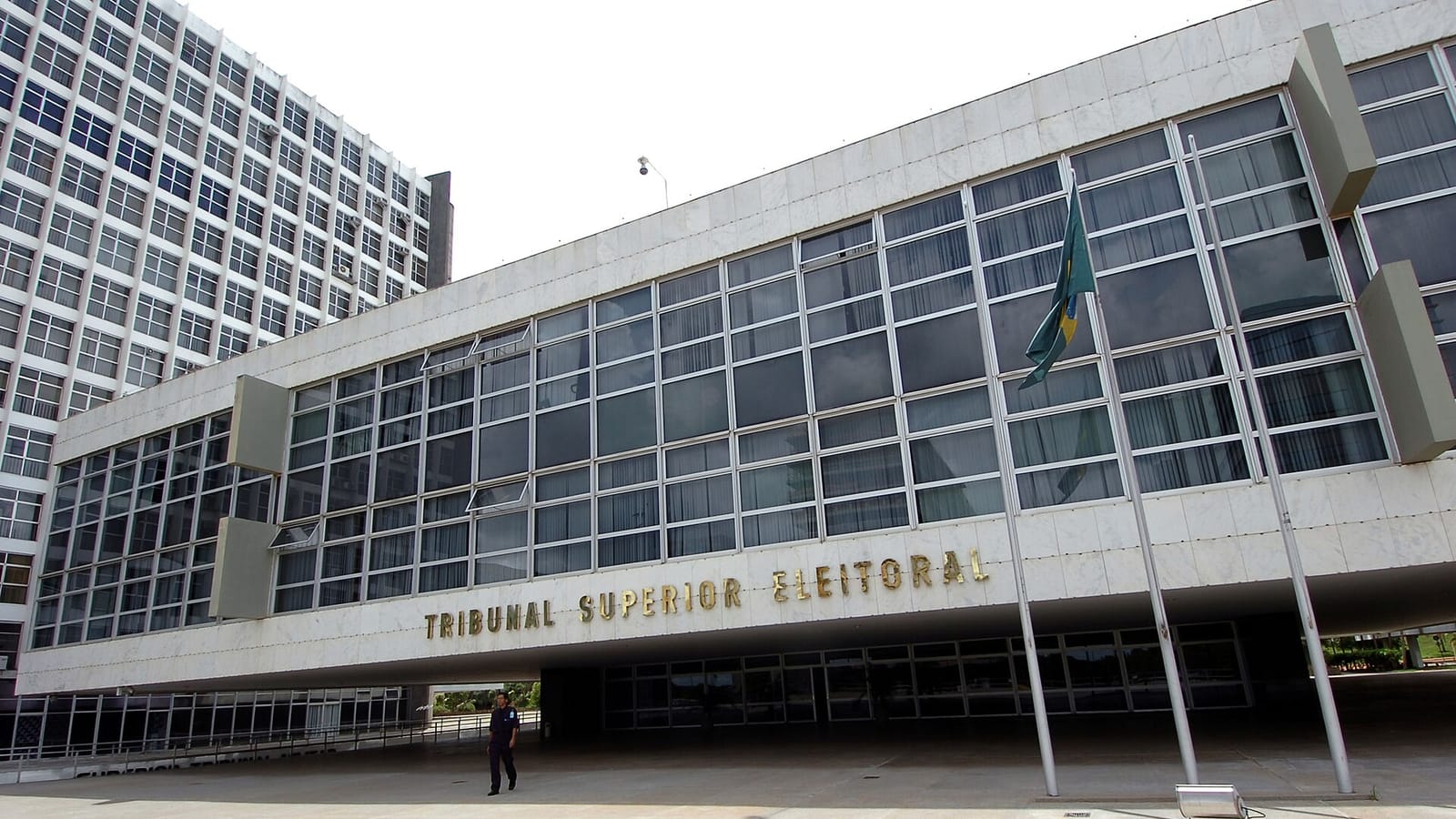 Urna eletrônica brasileira ao lado de documentos e um passaporte, em representação de uma decisão judicial ligada a uma eleição presidencial